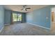 This bedroom features neutral carpeting, a ceiling fan, light blue walls and a window with curtains at 14352 Pocono Ave, Port Charlotte, FL 33981