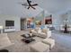 Living room with ample seating, ceiling fan, and open floor plan leading to the kitchen and dining area at 14352 Pocono Ave, Port Charlotte, FL 33981