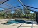 Screened in backyard pool with a concrete deck and spa with surrounding trees at 14352 Pocono Ave, Port Charlotte, FL 33981