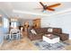 Open-concept living room featuring a large sectional sofa, ceiling fan, and travertine tile flooring at 1440 Overbrook Rd, Englewood, FL 34223
