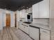 Modern kitchen with white cabinets, stone backsplash, and a black countertop with brass fixtures at 1503 Marlin St, Nokomis, FL 34275