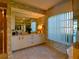Spacious bathroom with a large mirror, white cabinetry, and a shower with glass enclosure at 1611 Valley Dr, Venice, FL 34292