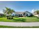 Well-maintained single-story home with a manicured lawn, tropical palm trees, and colorful flowerbeds at 1611 Valley Dr, Venice, FL 34292