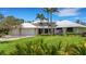 Stunning home features a metal roof, three-car garage, and lush landscaping with palm trees against a clear blue sky at 1657 Bayshore Dr, Englewood, FL 34223