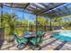 Outdoor patio features a covered dining area with a table and chairs next to a swimming pool and lush landscaping at 1657 Bayshore Dr, Englewood, FL 34223
