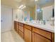 Bright bathroom featuring double sinks, a spacious counter, wood cabinets, and a large mirror at 19124 Mangieri St, Venice, FL 34293