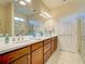 Bright bathroom showcasing double sinks, wooden cabinets, and large mirror; adjacent to a glass-enclosed shower at 19124 Mangieri St, Venice, FL 34293