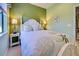 This bedroom features light green walls, a white bed frame, and matching end tables with lamps at 19124 Mangieri St, Venice, FL 34293