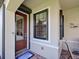 Close-up of front door with glass panels, sidelight, and a welcome mat on a covered porch with brick flooring at 19124 Mangieri St, Venice, FL 34293
