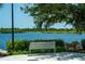 Scenic lake view with a bench under a tree, perfect for relaxing and enjoying the natural surroundings at 19124 Mangieri St, Venice, FL 34293