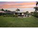 Picturesque backyard with a screened-in lanai, outdoor seating area, lush green lawn, and tropical landscaping at sunset at 19893 Cobblestone Cir, Venice, FL 34292