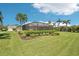 Expansive backyard with lush green lawn, screened-in lanai, and manicured landscaping at 19893 Cobblestone Cir, Venice, FL 34292