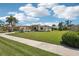 Charming single-story home featuring a landscaped lawn, mature trees, well-lit walkway, and a convenient two-car garage at 19893 Cobblestone Cir, Venice, FL 34292