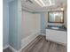 Bathroom features a tub with white tile surround, blue walls, wood-look flooring and modern vanity at 200 Sierra S St, Nokomis, FL 34275