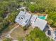 Estate aerial showcasing a large home with metal roof, circular drive, and luxury pool nestled amongst lush trees at 202 Laurel Oaks Rd, Nokomis, FL 34275