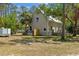 Side view of a two-story home with a metal roof, lawn, and mature tree in front at 202 Laurel Oaks Rd, Nokomis, FL 34275