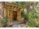 Picture of the decorated wooden outhouse with a roof, surrounded by luscious green plants and tropical palms at 202 Laurel Oaks Rd, Nokomis, FL 34275