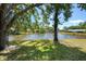 View of the water in backyard with mature trees, lush grass, and landscaping at 226 Southampton Ln # 257, Venice, FL 34293