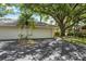 Spacious driveway leading to a two-car garage, surrounded by mature landscaping and trees at 226 Southampton Ln # 257, Venice, FL 34293