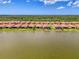 Aerial view of homes overlooking lake, showcasing lush landscaping and red tile roofs at 24128 Spartina Dr, Venice, FL 34293