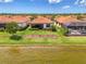 Backyard view featuring lush green lawn, mature landscaping, and a screened lanai overlooking the lake at 24128 Spartina Dr, Venice, FL 34293