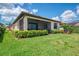 Beautiful backyard featuring manicured lawn, mature landscaping, and a screened lanai for outdoor living at 24128 Spartina Dr, Venice, FL 34293