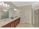 Well-lit bathroom featuring dual sinks, granite countertops, a glass-enclosed shower, and neutral tile flooring at 24128 Spartina Dr, Venice, FL 34293