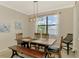 Bright dining room with wood table and bench seating, complemented by elegant lighting and serene water view at 24128 Spartina Dr, Venice, FL 34293