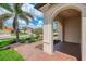 Exterior view from covered entry showing lush tropical landscaping and a brick walkway at 24128 Spartina Dr, Venice, FL 34293