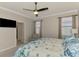 Bright main bedroom with ceiling fan, comfortable chair, and a bed with a seashell pattern comforter at 24128 Spartina Dr, Venice, FL 34293