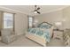 Inviting bedroom showcasing a bed with a blue seashell-patterned comforter, ceiling fan, and two windows at 24128 Spartina Dr, Venice, FL 34293
