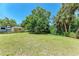 Spacious backyard with lush green lawn, mature trees, and a trailer parked on the side at 2641 Hyde Park St, Sarasota, FL 34239