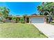 Charming single-story home with a well-manicured lawn, mature trees, and an attached two-car garage at 2641 Hyde Park St, Sarasota, FL 34239