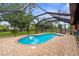Screened in pool and brick patio with shade trees in background at 304 Beach Rd, Venice, FL 34285