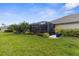Well-maintained backyard with lush green grass, landscaping, and a screened-in lanai at 3419 Lakewood Blvd, North Port, FL 34287