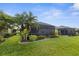Landscaped backyard with manicured lawn, shrubs and palm trees, and a screened-in lanai at 3419 Lakewood Blvd, North Port, FL 34287