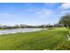 Scenic backyard featuring a calm lake, green lawn, and tropical palm trees, creating a tranquil setting at 3419 Lakewood Blvd, North Port, FL 34287