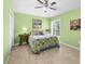 Sunlit bedroom with green walls, a ceiling fan, tile flooring, and a cozy quilt-covered bed at 3419 Lakewood Blvd, North Port, FL 34287
