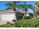 Inviting home exterior with a two-car garage, complemented by vibrant landscaping and mature palm trees at 3419 Lakewood Blvd, North Port, FL 34287