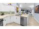 The kitchen has stainless steel dishwasher and sink, white cabinets and tile floors at 3419 Lakewood Blvd, North Port, FL 34287