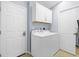 Functional laundry room with white washer and dryer, storage cabinets, and neutral tile flooring at 3419 Lakewood Blvd, North Port, FL 34287
