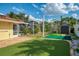 View of backyard putting green with tropical landscaping and shed at 403 Picasso Dr, Nokomis, FL 34275