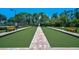 Community bocce ball court with artificial turf surrounded by benches and beautiful landscaping at 4321 Via Del Santi Dr, Venice, FL 34293