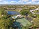 An aerial view of a neighborhood with a lake, swimming pool, and tennis courts nestled within a lush, green landscape at 442 Sunset Lake Blvd # 104, Venice, FL 34292