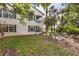 Exterior view of a two-story home with manicured lawn and a lakeside view, enhanced by mature trees and lush landscaping at 442 Sunset Lake Blvd # 104, Venice, FL 34292