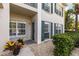 Inviting condo entrance with decorative potted plants, lush greenery, and shuttered windows at 442 Sunset Lake Blvd # 104, Venice, FL 34292
