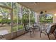 Relaxing screened lanai with seating area offering views of the lush green landscaping at 442 Sunset Lake Blvd # 104, Venice, FL 34292