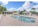 Beautiful pool surrounded by a large brick patio, comfortable lounge chairs, and a covered area at 442 Sunset Lake Blvd # 104, Venice, FL 34292