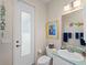 Cozy bathroom featuring a toilet, single sink, vanity and a frosted glass exterior door at 5035 Collingswood Blvd, Port Charlotte, FL 33948