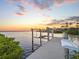 Private dock on the water featuring boat lift, sunset views, and tropical landscaping at 5035 Collingswood Blvd, Port Charlotte, FL 33948